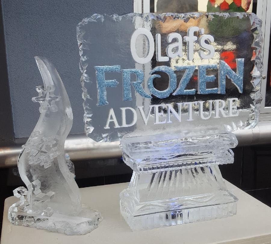 Olaf’s Frozen Adventure ice sculpture with a small Olaf figure on the left and sign on the right