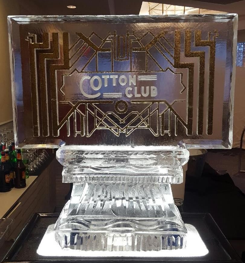 Gold Cotton Club sign on a clear ice pedestal, lit from below at an event table