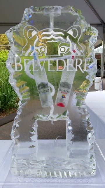 Clear ice sculpture of a BEVERLY sign with a wine glass and decorative floral shapes outdoors