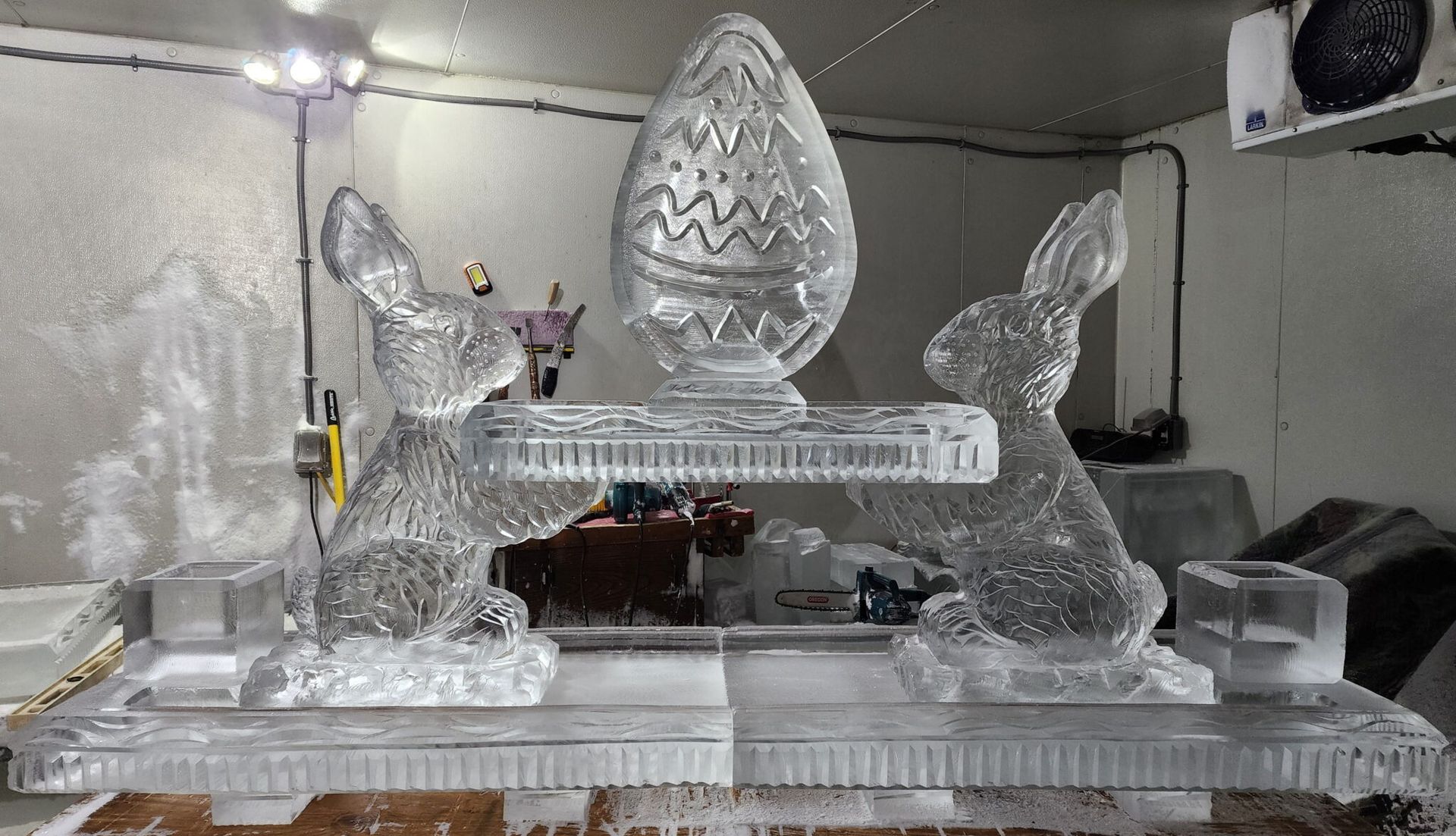 Ice sculpture display with an egg-shaped centerpiece on a decorated platform indoors