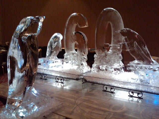 Ice sculpture display of penguins and the number 60 on a lit platform