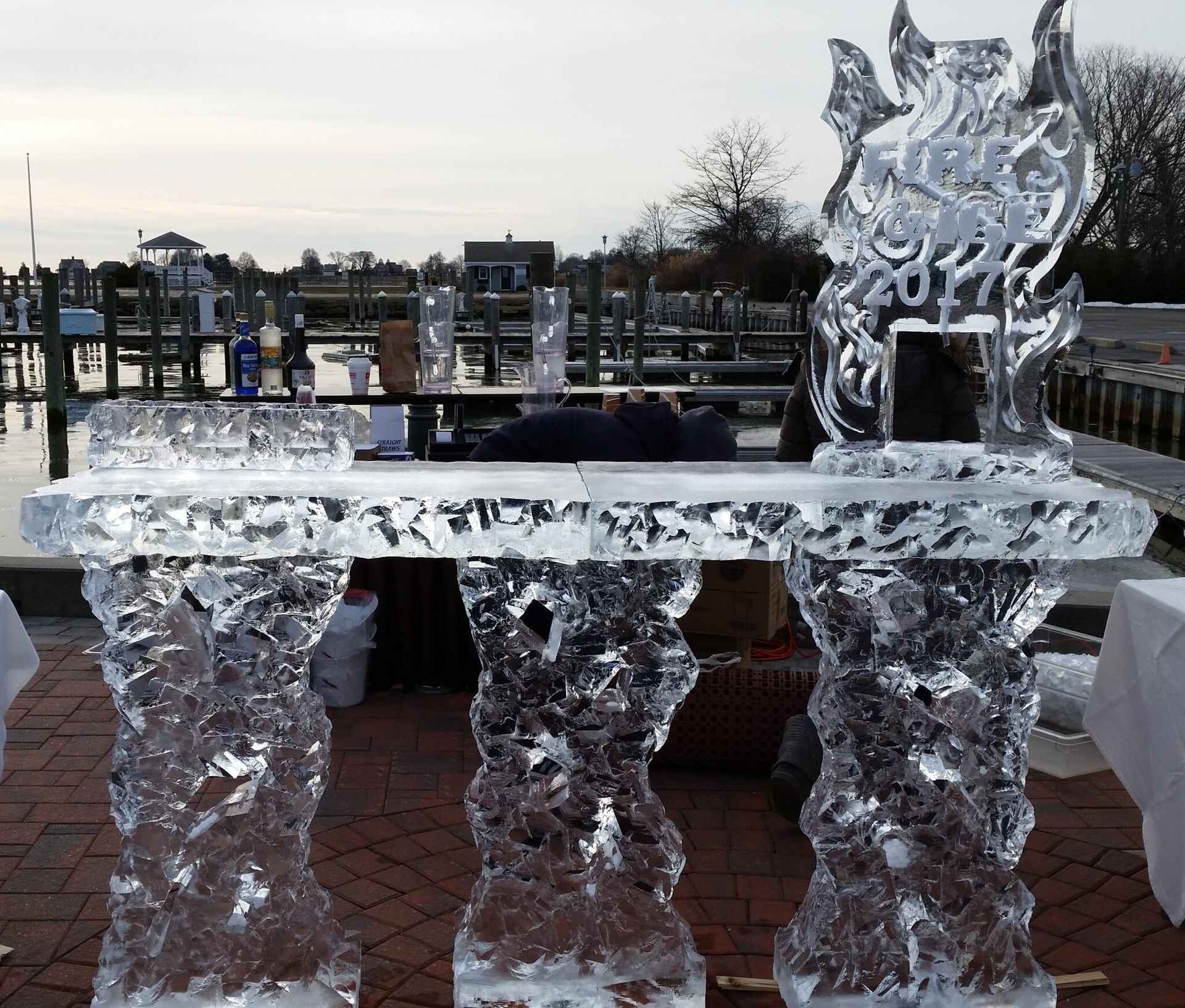 Ice sculpture of a table and chairs outdoors on a brick patio by the water