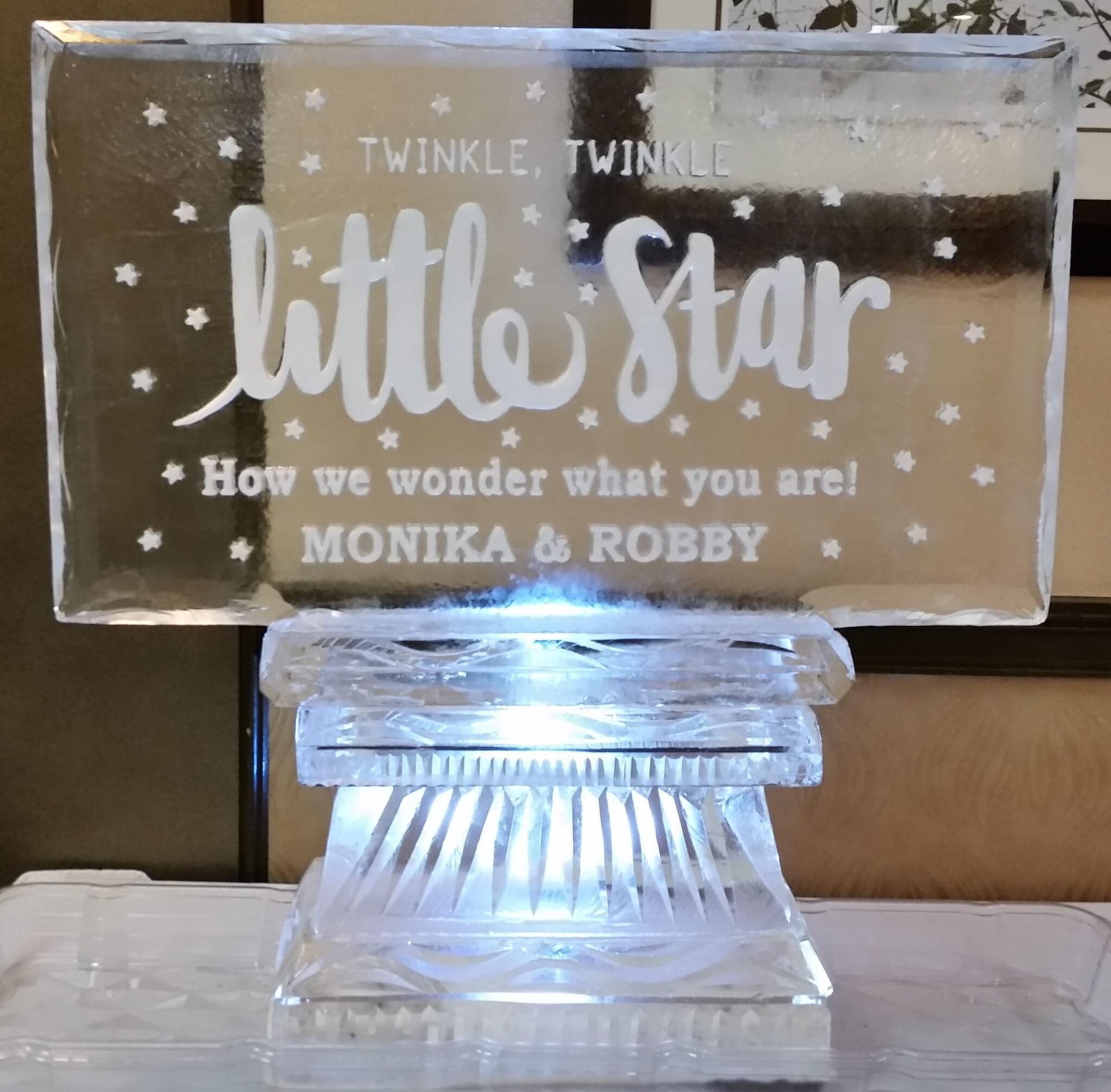 Clear engraved plaque reading “Twinkle, Twinkle little Star” on a lit crystal stand with stars and names Monika & Robby