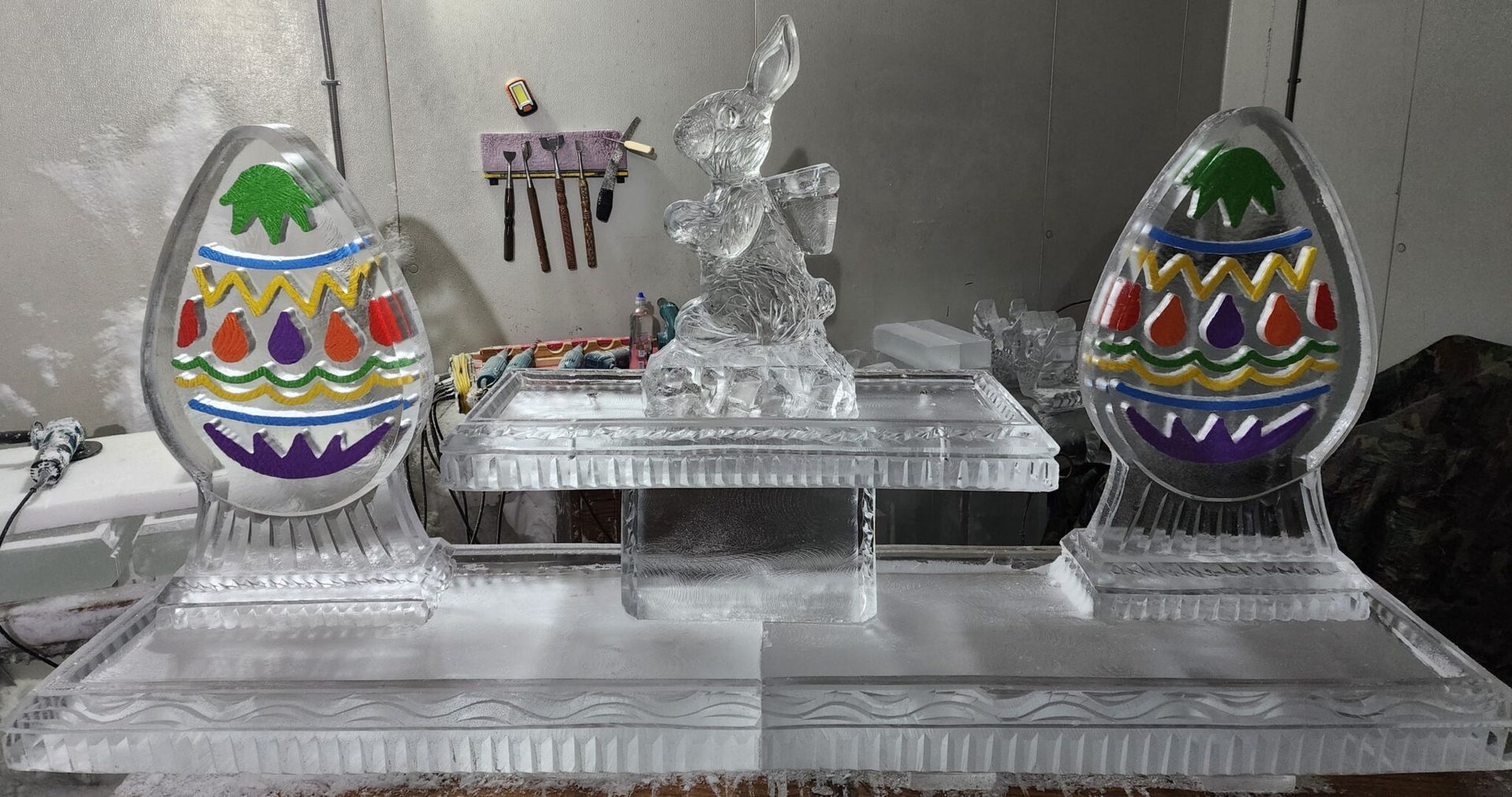 Decorative silver display with two colorful Easter eggs and a central angel figurine on mirrored trays