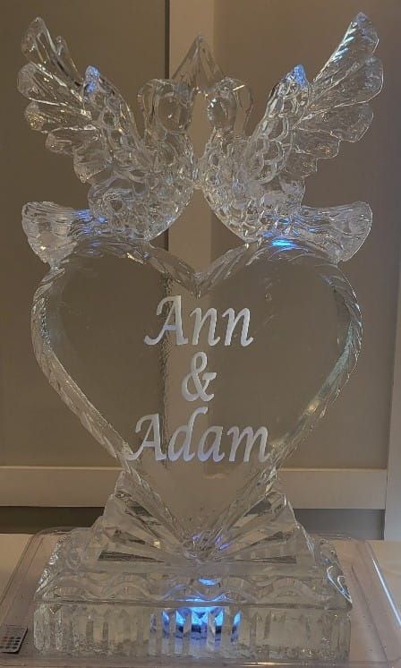 Clear crystal heart plaque with angel wings and the names “Ann & Adam” engraved on it.