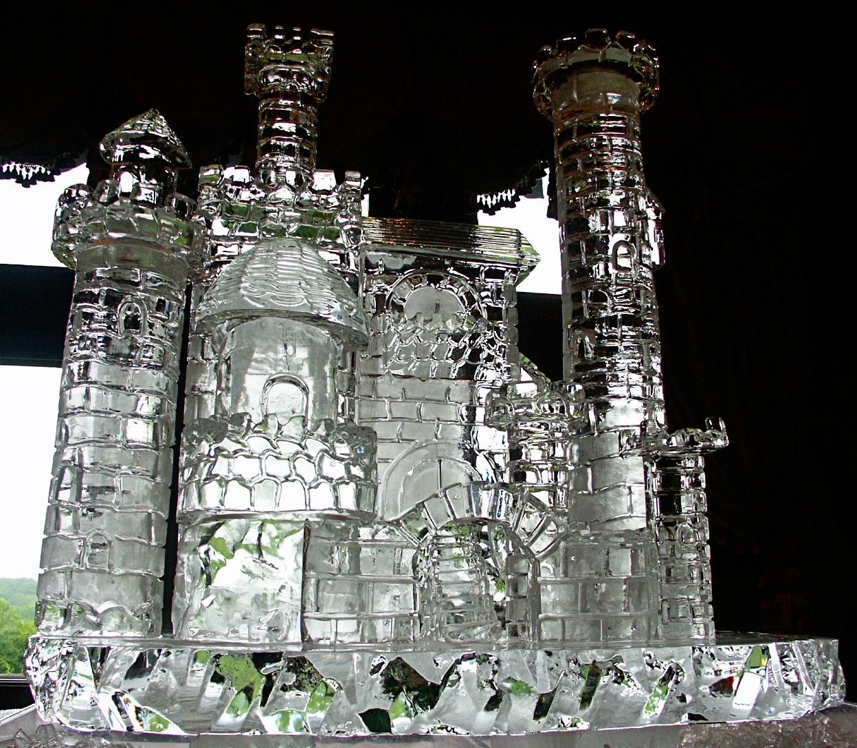 Crystal castle sculpture with towers on a clear base, lit against a dark background
