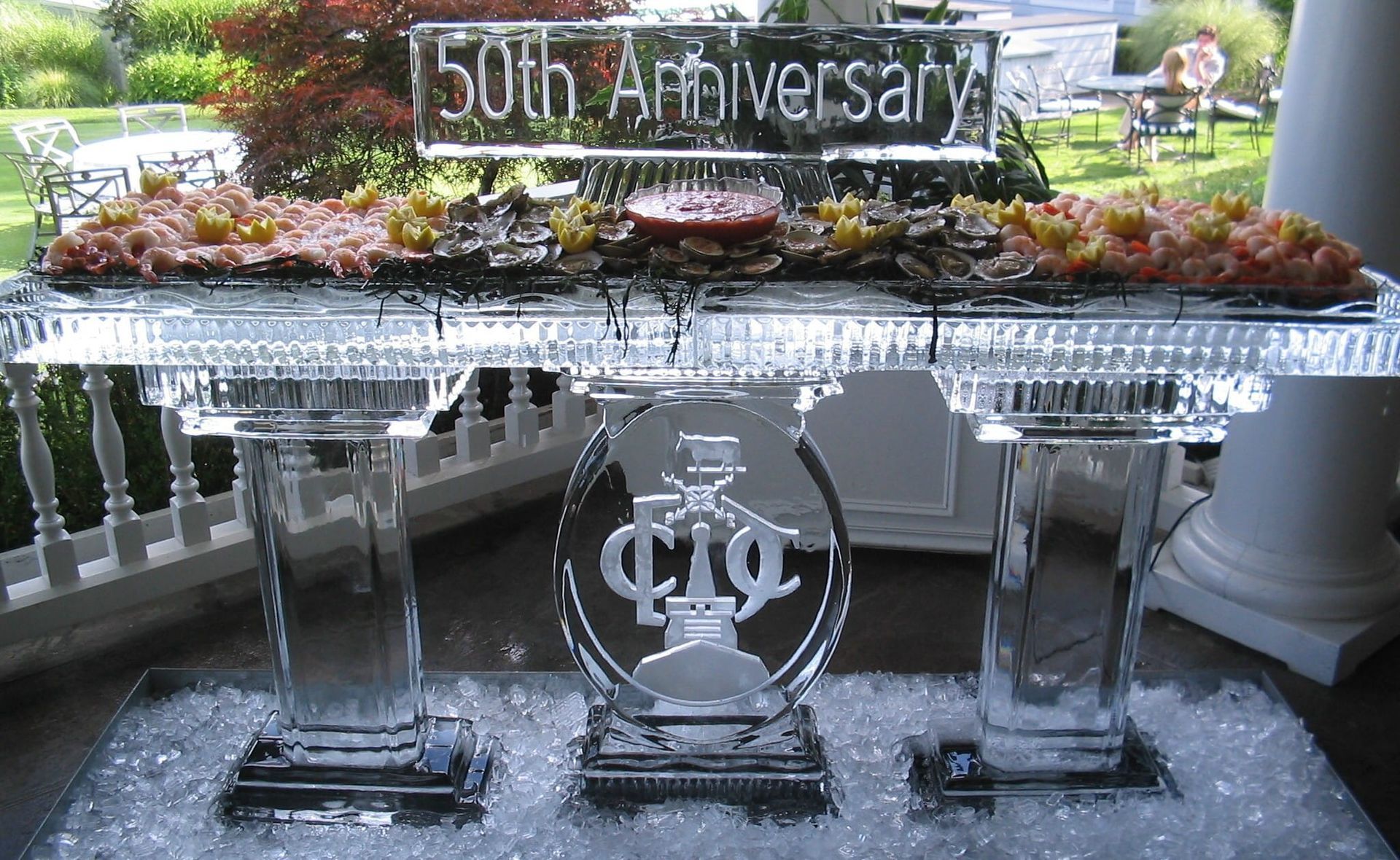 50th anniversary floral centerpiece with frosted-glass awards on a reflective table