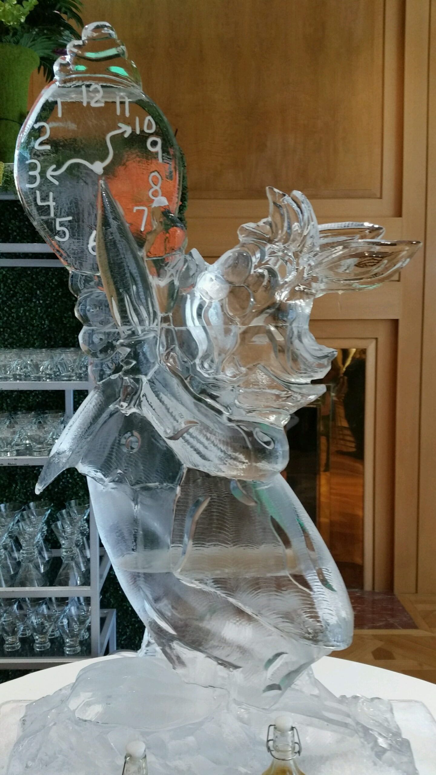 Translucent glass horse sculpture on a base, with a clock-like face in the background