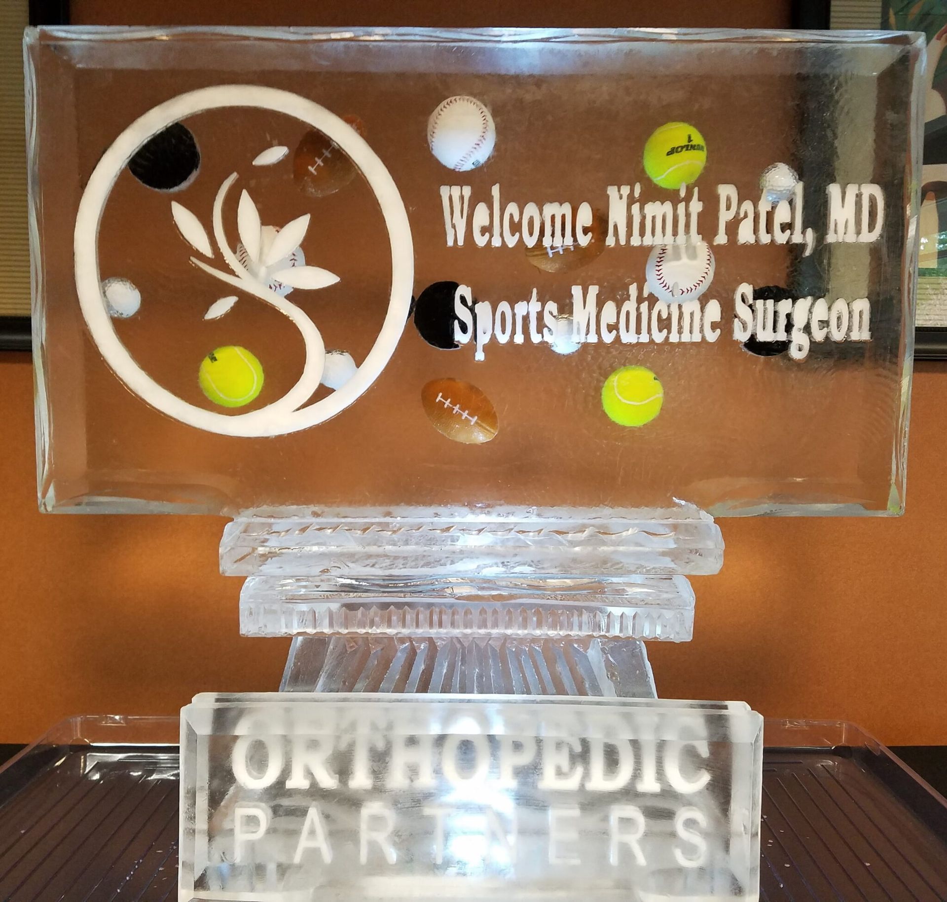 Clear acrylic desk plaque for “Welcome Nimit Patel, MD, Sports Medicine Surgeon” on an Orthopedic Partners base