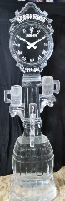 Clear glass tabletop clock with ornate top, displayed on a transparent pedestal against a dark background