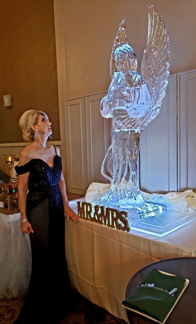 Woman in black dress beside a glowing ice sculpture and PRPIRS sign at an indoor event