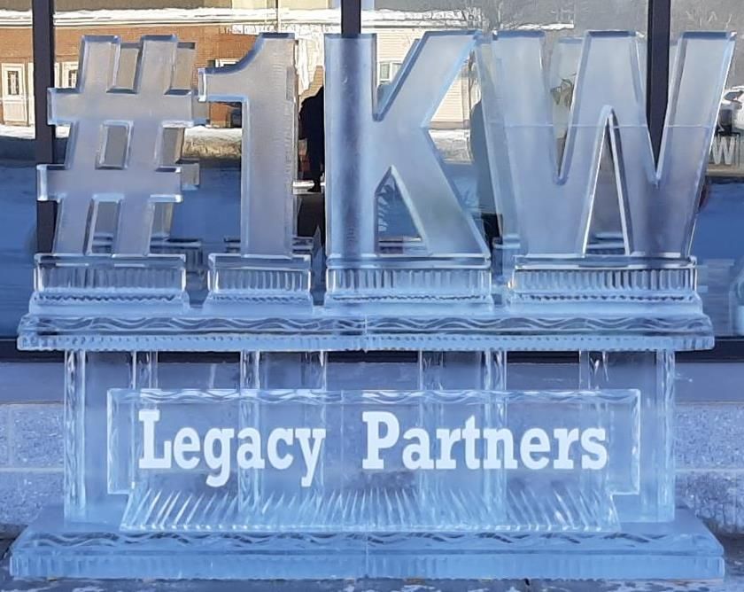 Ice sculpture reading “#1 KW” with “Legacy Partners” etched below, displayed outdoors.