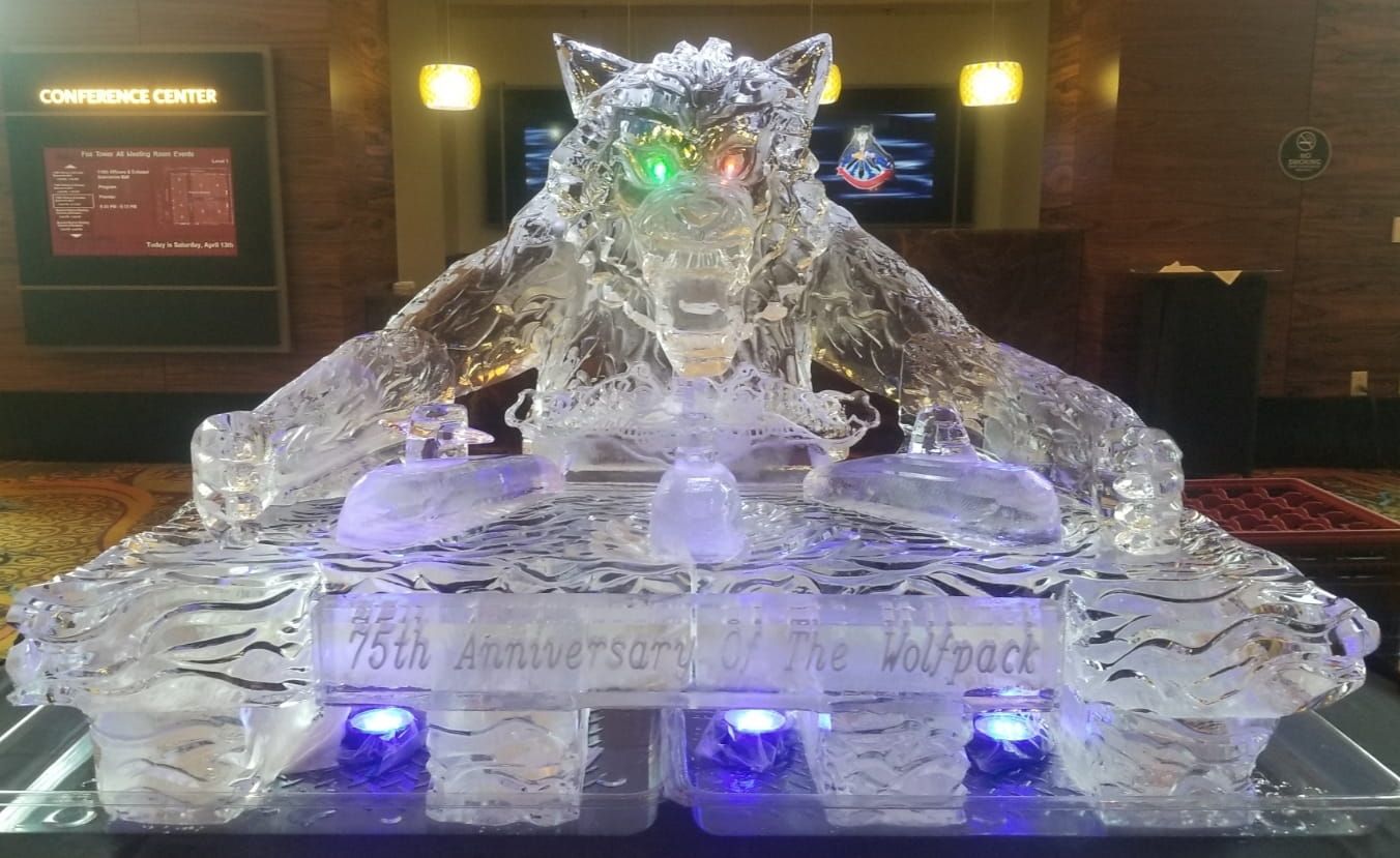 Crystal ice sculpture of a reclining wolf or dragon, lit green, on a base in a dim lobby or exhibit hall