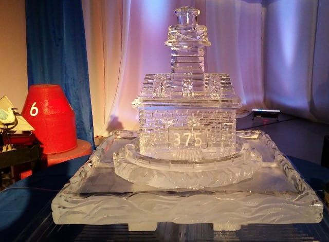 Transparent layered cake on a tray, lit by purple lights, with a red container marked “6” beside it.
