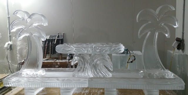Transparent glass sculpture of palm trees on a pedestal in a room