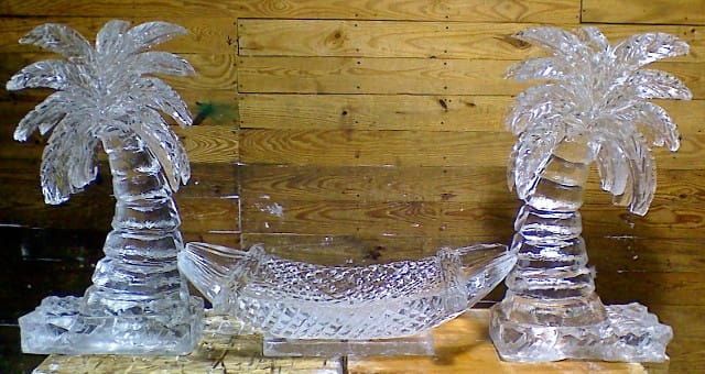 Clear glass palm tree candle holders with a curved matching center piece on a wooden surface