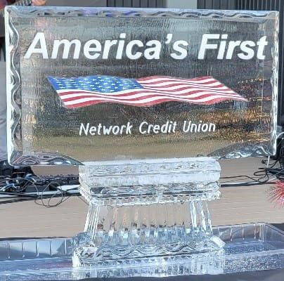 Ice sculpture plaque reading “America’s First Network Credit Union” with an American flag design