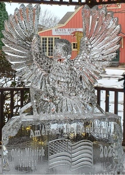 Ice sculpture of a winged eagle on a pedestal in an outdoor winter setting