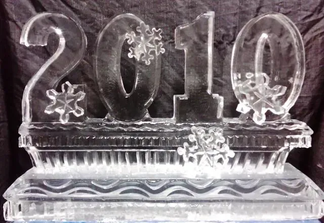 Clear ice sculpture of “2010” with snowflakes on a decorative base
