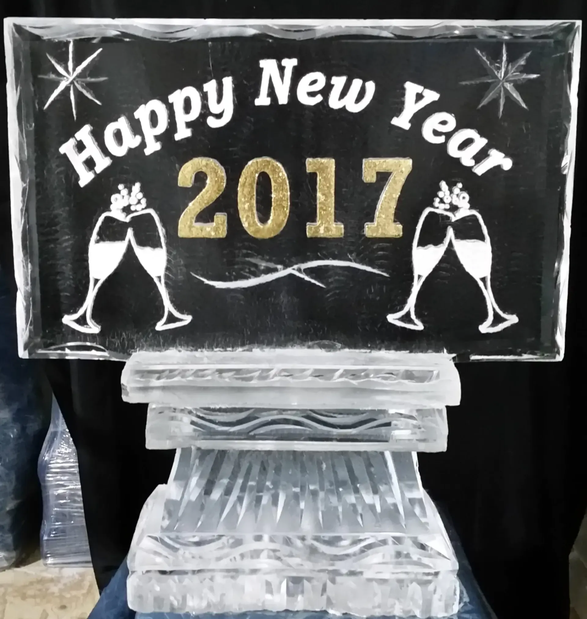 Happy New Year 2017 sign on black background with champagne glasses and ice sculpture pedestal