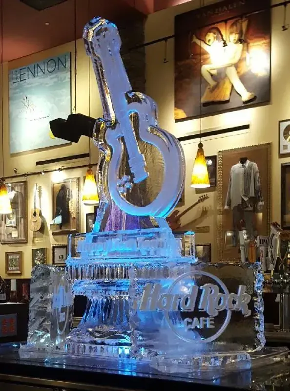 Blue-lit ice sculpture of a guitar with Hard Rock Cafe logo inside a restaurant display