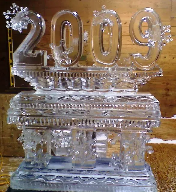 Clear ice sculpture with “2009” on a pedestal against a wooden background