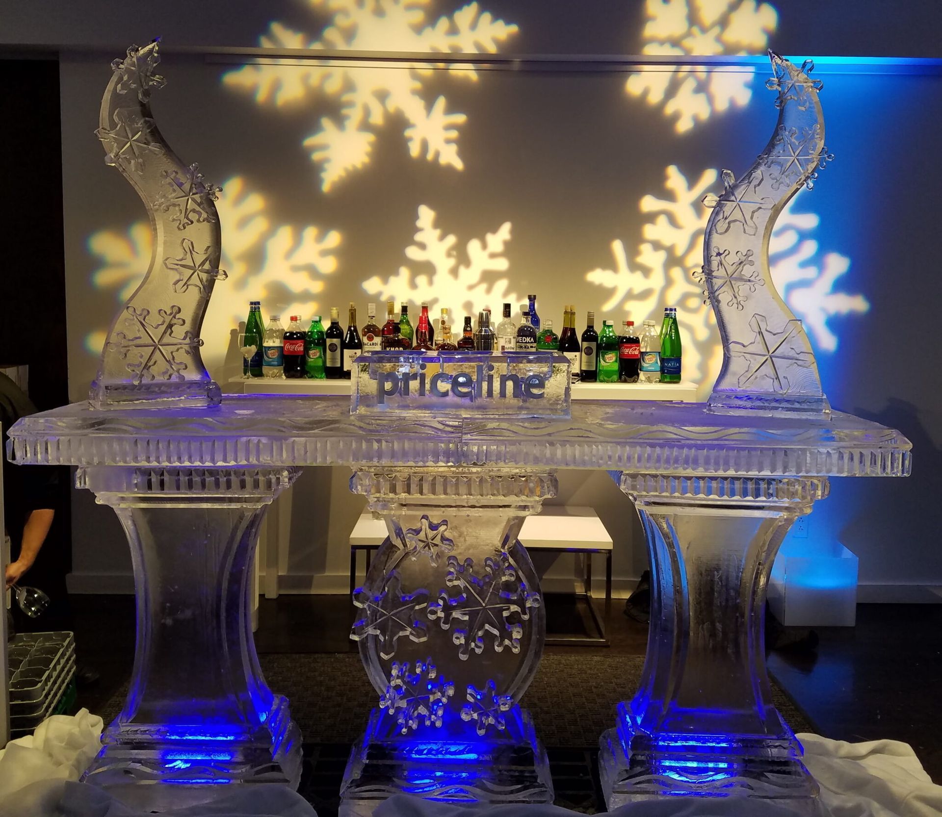 Ice-sculpture bar display with blue lights and snowflake shadows on a wall