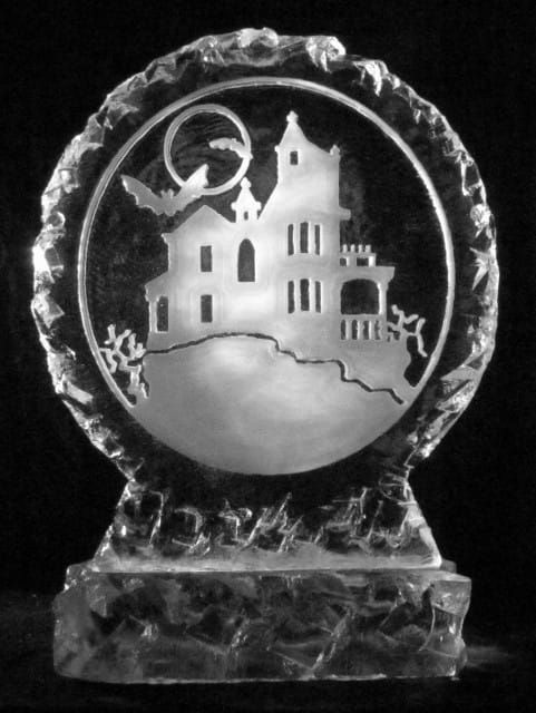 Decorative glass plaque with a house silhouette under a moon and stars on a pedestal