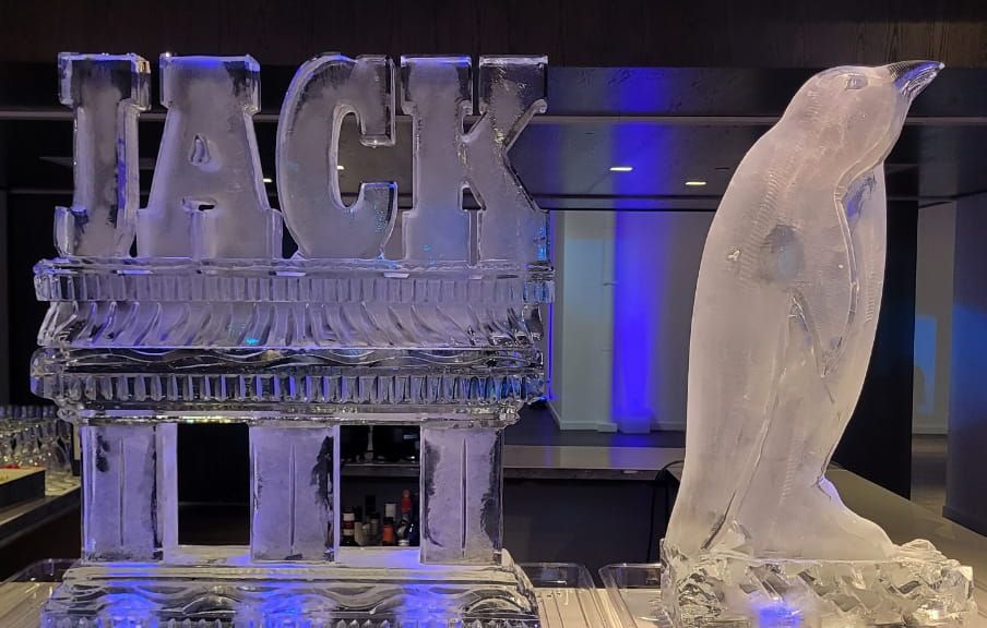 Ice sculpture of “JACK” next to a penguin in a blue-lit display