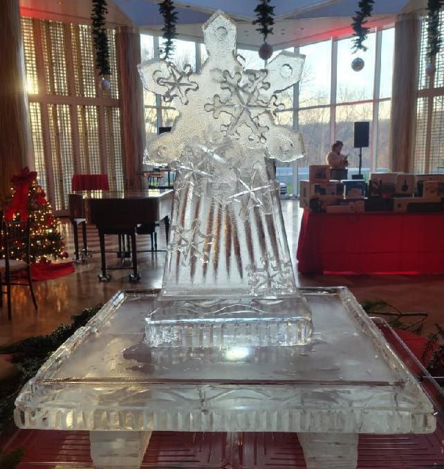 Ice sculpture of a star on a pedestal in a festive indoor hall with holiday decorations
