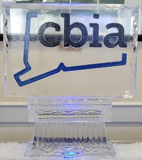 CBIA logo in dark blue on a clear acrylic sign with a blue base on a table