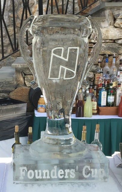Glass “Founders’ Cup” trophy with an H logo, displayed on a bar counter with bottles in the background