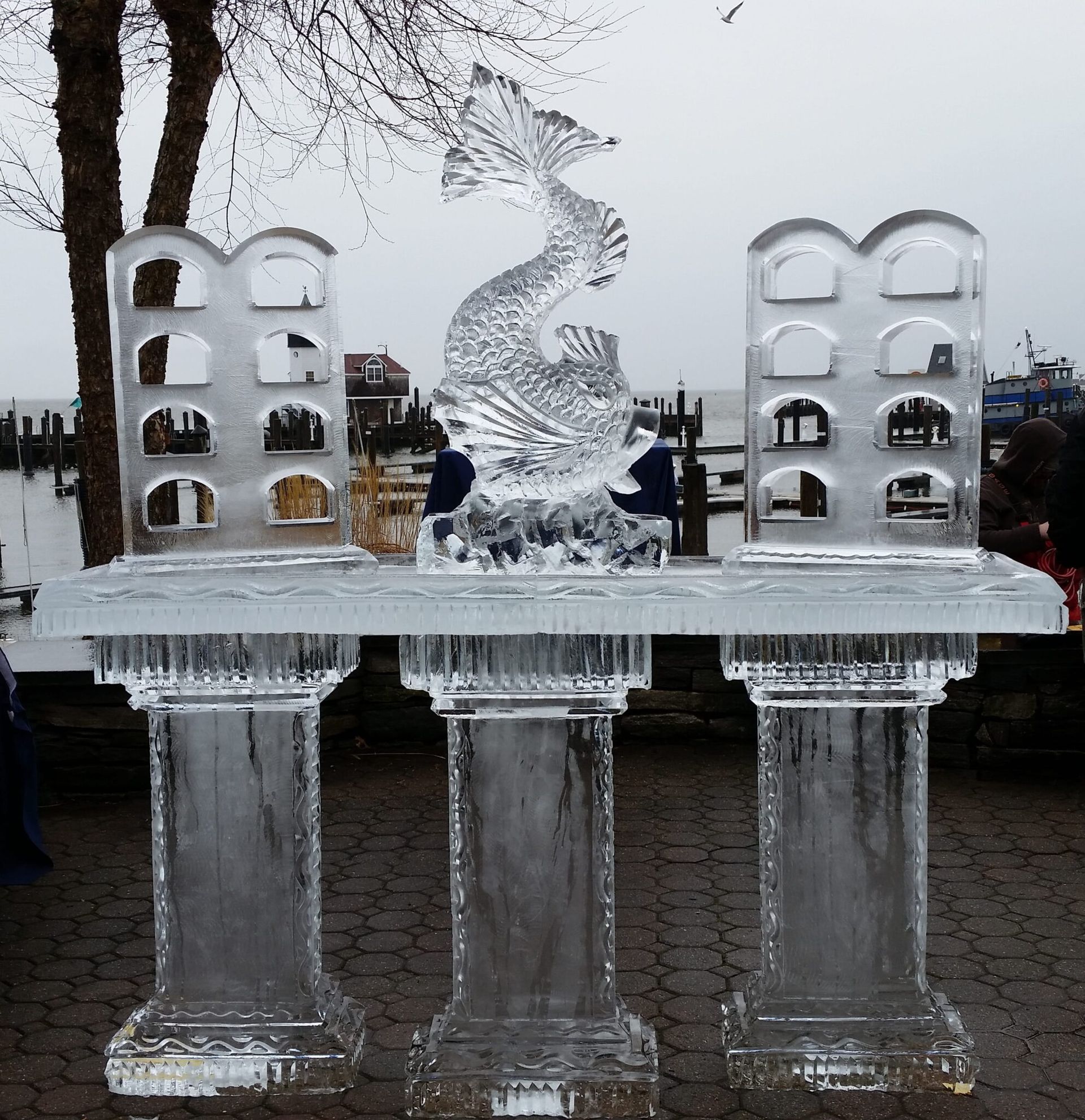 Ice sculpture fountain with arched blocks and clear columns outdoors on a cloudy day