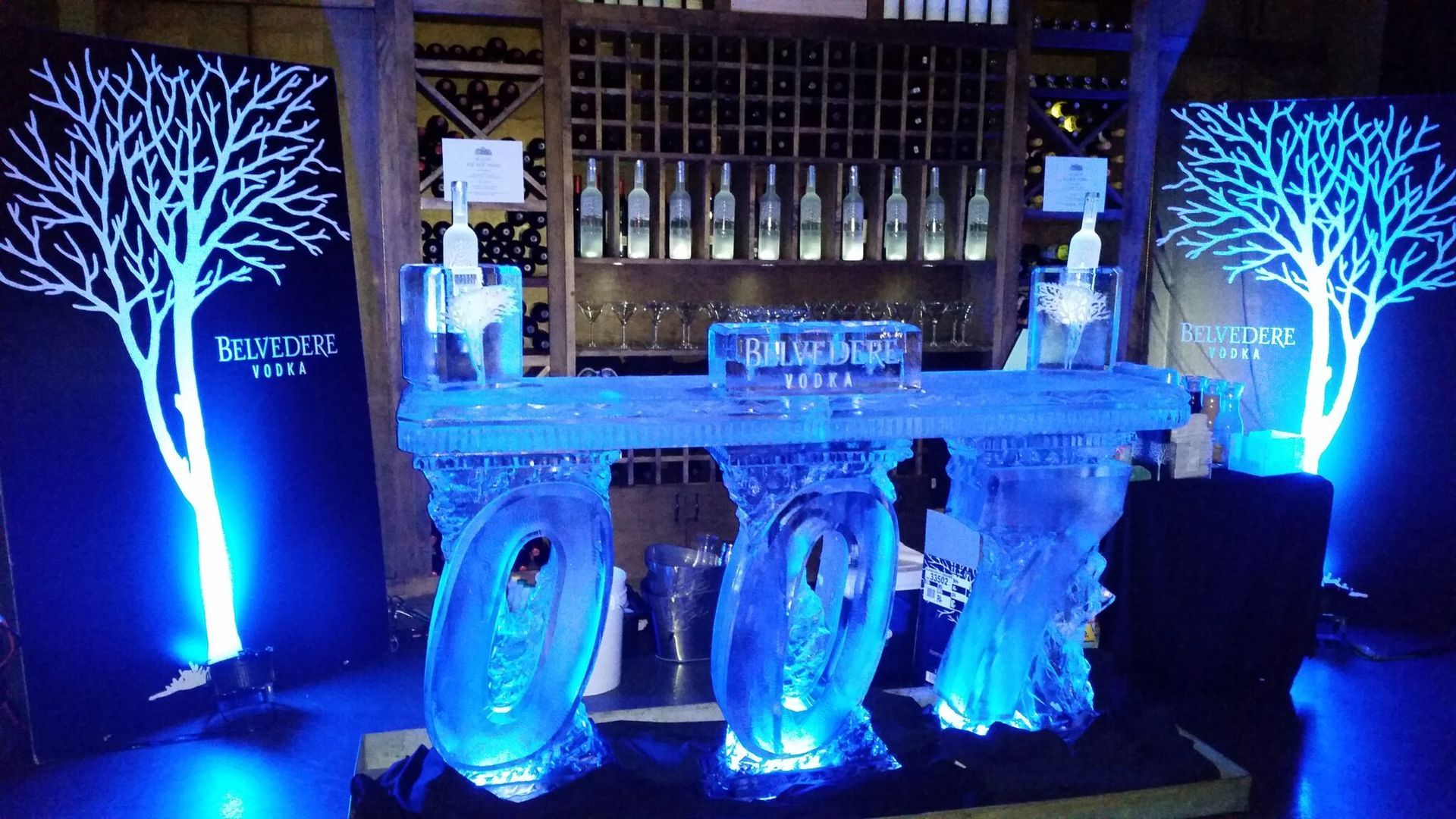 Blue-lit ice bar with carved icy stools and glowing tree decorations indoors
