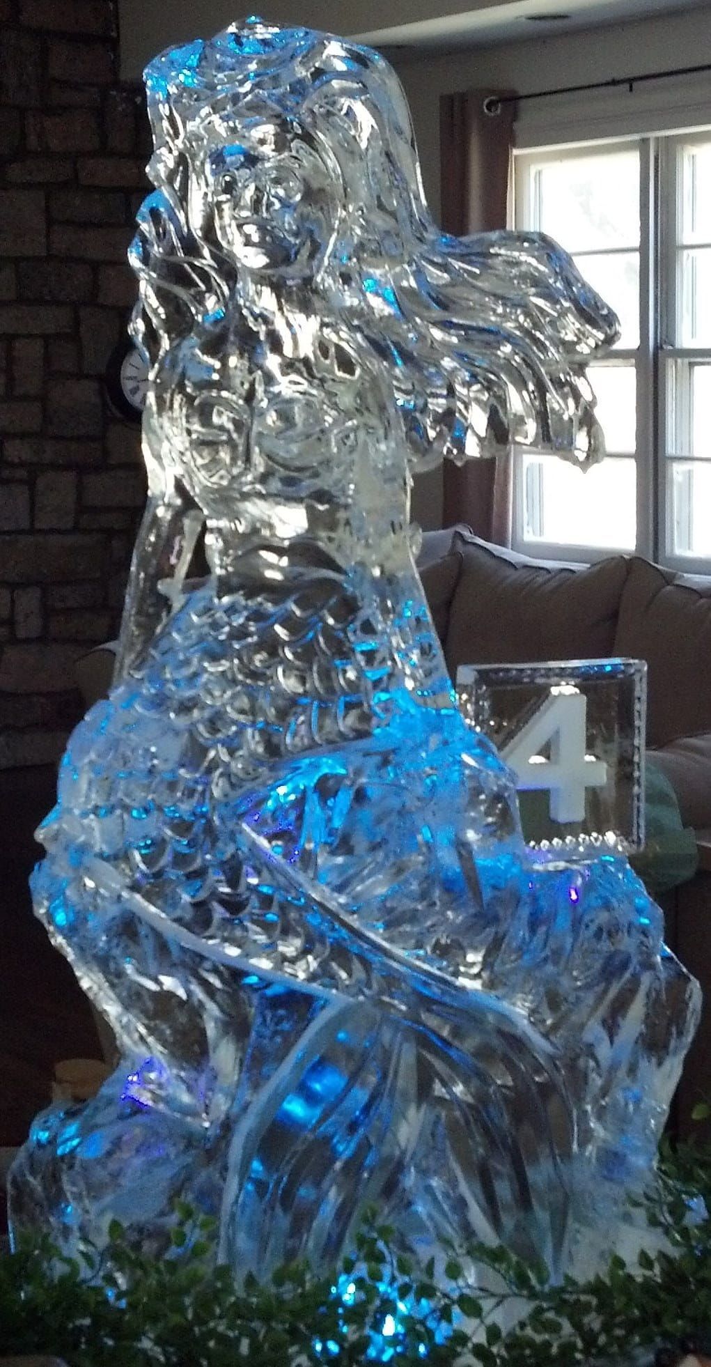Shiny silver ice sculpture in a room, lit blue, with a number 4 sign in front