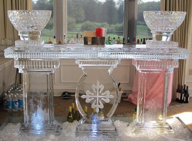 Crystal bar cart with glass bowls and a pink drink in a bright room by a window