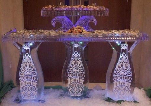 Three illuminated glass bottles beneath a lit tray on a cotton-like base, displayed on a dark background.