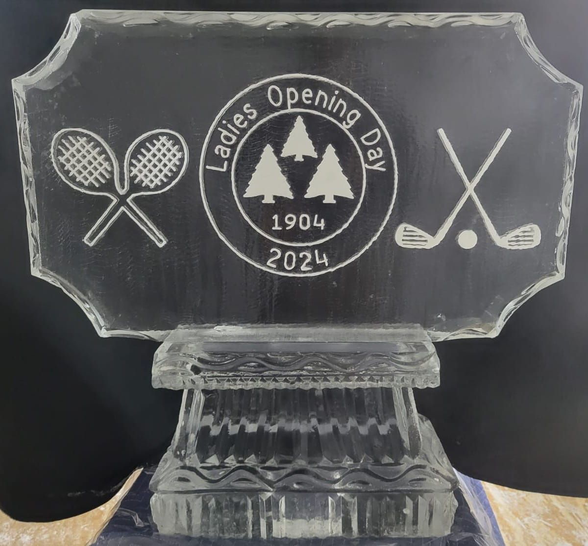 Etched glass plaque with tennis rackets, trees, and “Ladies Opening Day 1904 2024” on a black background