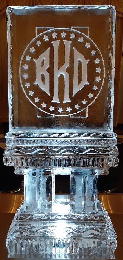 Clear glass award with a circular monogram and stars on a pedestal base