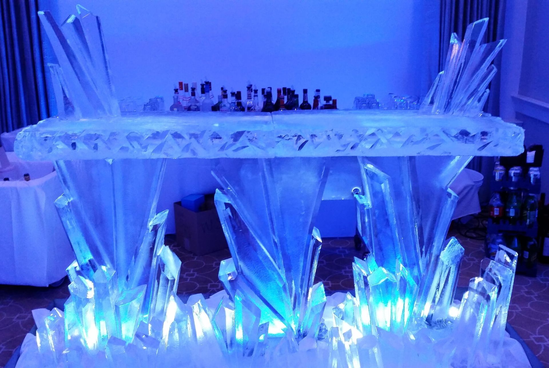 Blue-lit ice sculpture with crystalline spikes and a decorative display on top