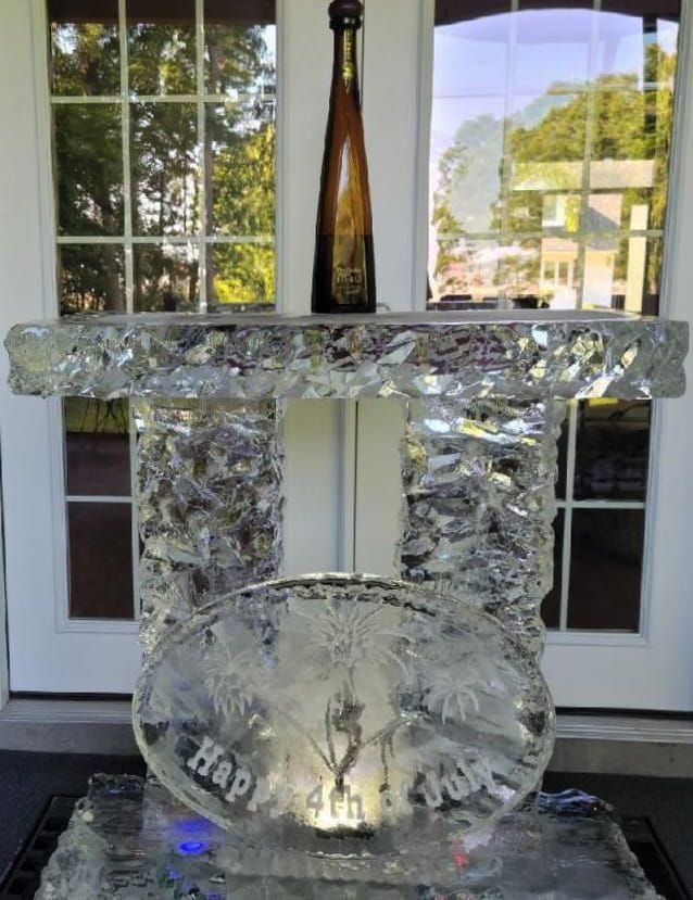 Ice sculpture table centerpiece with a bottle on top, displayed in front of a window.