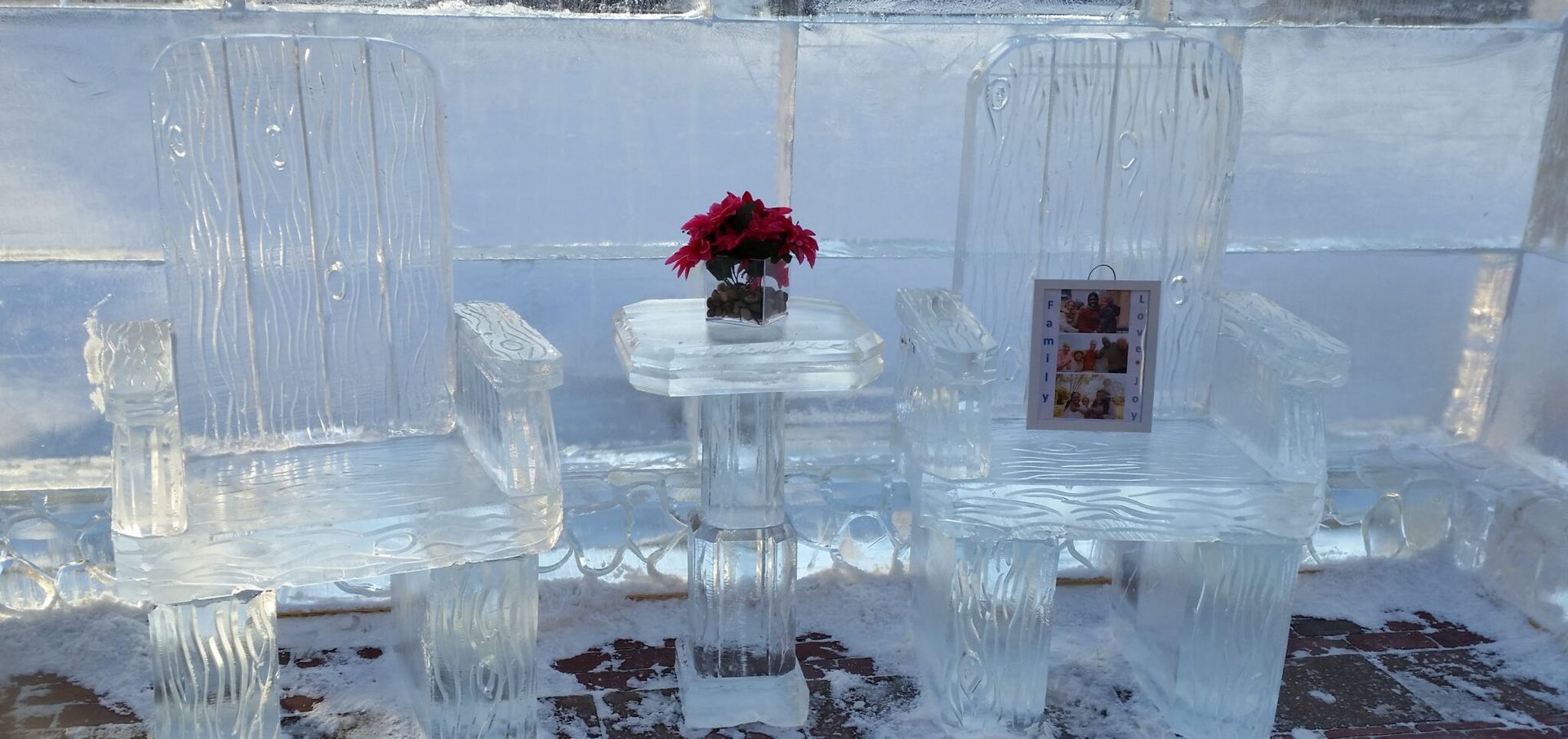 Ice sculpture wall with a small vase of red flowers centered on a table