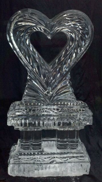 Clear glass heart-shaped trophy on a pedestal against a dark background