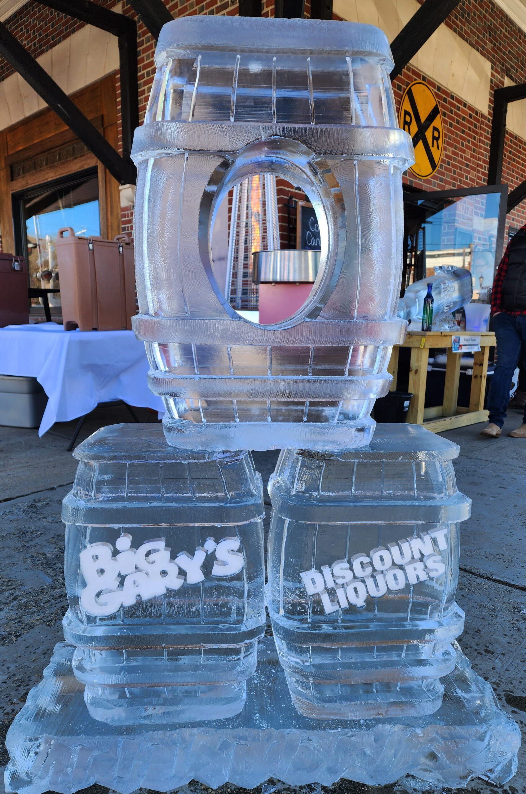 Clear stacked ice sculpture with a circular opening, displayed indoors on a decorated table