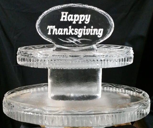 Clear glass pedestal plate with “Happy Thanksgiving” sign on black background