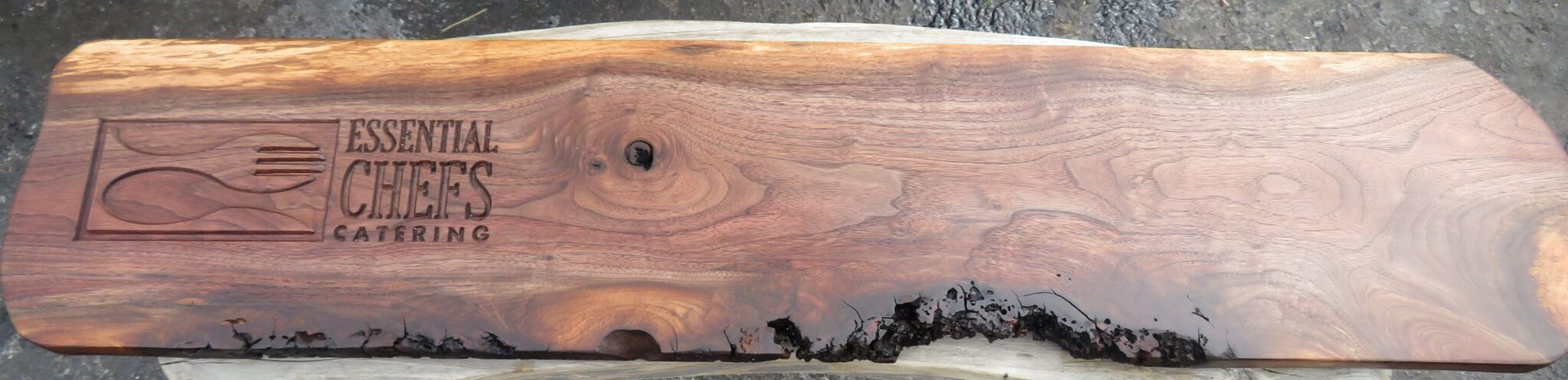 Close-up of a carved wooden plaque with an engraved logo and text, featuring a natural bark edge.