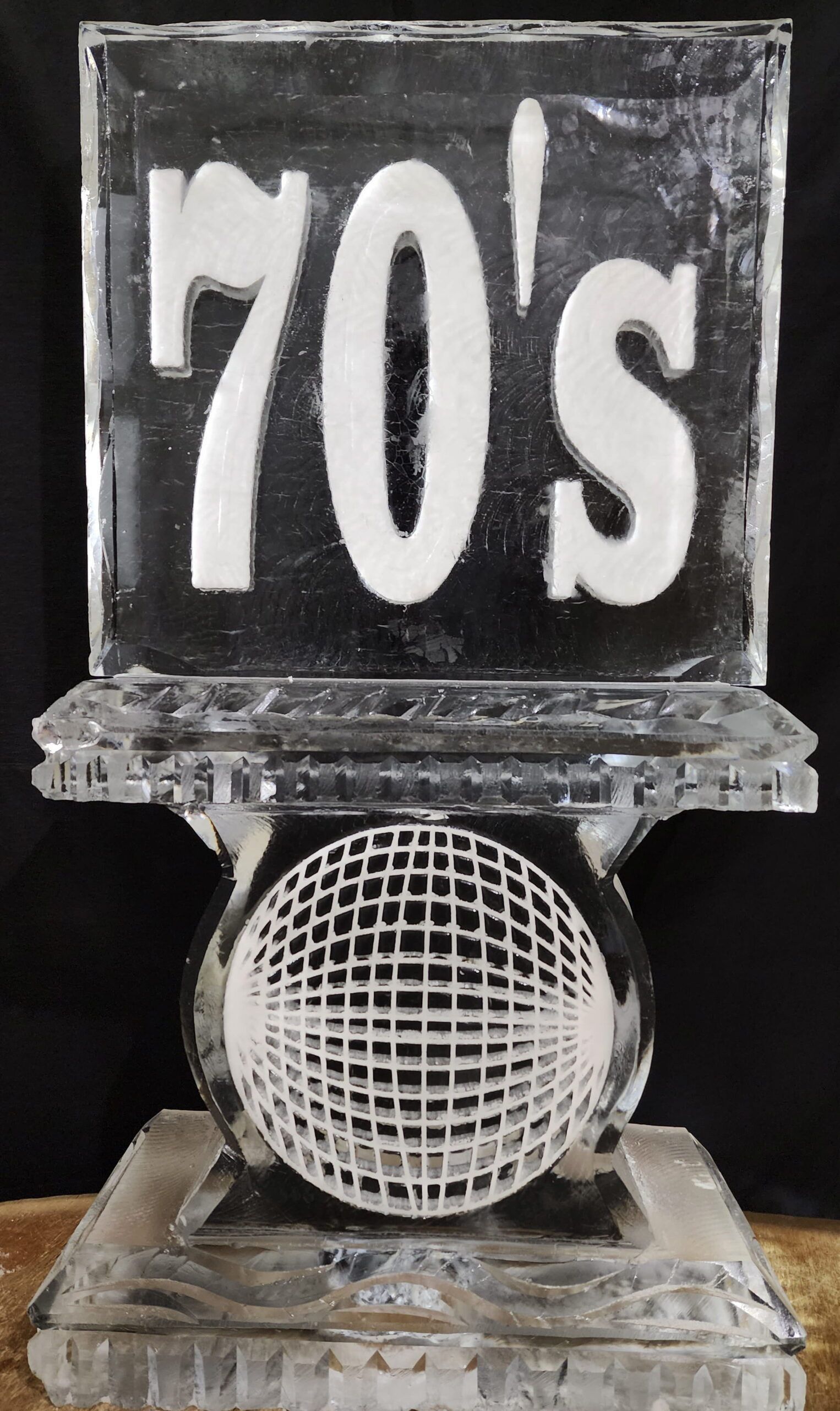Clear glass decorative block with “70s” above a textured glass sphere on a clear base