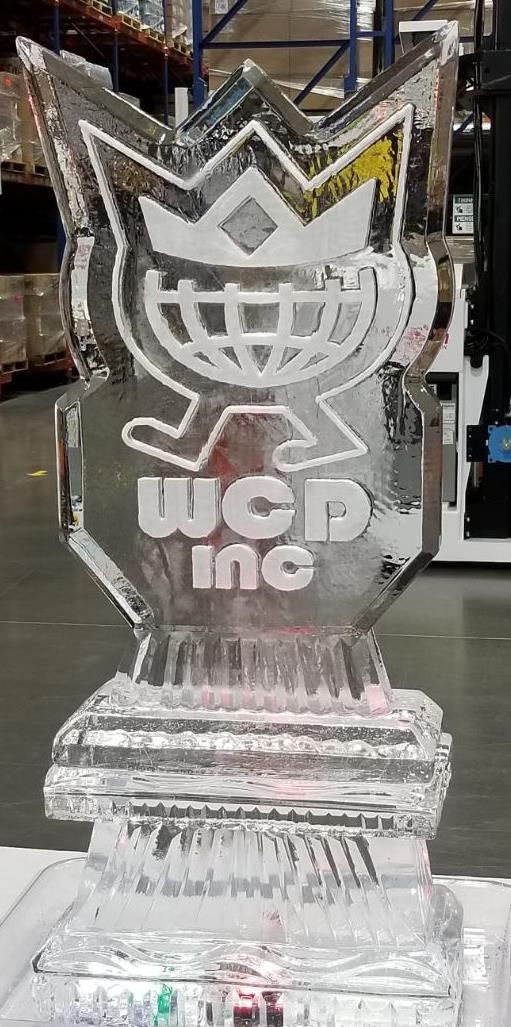 Clear acrylic trophy with a crown logo and “WCD INC” on a base, displayed indoors.
