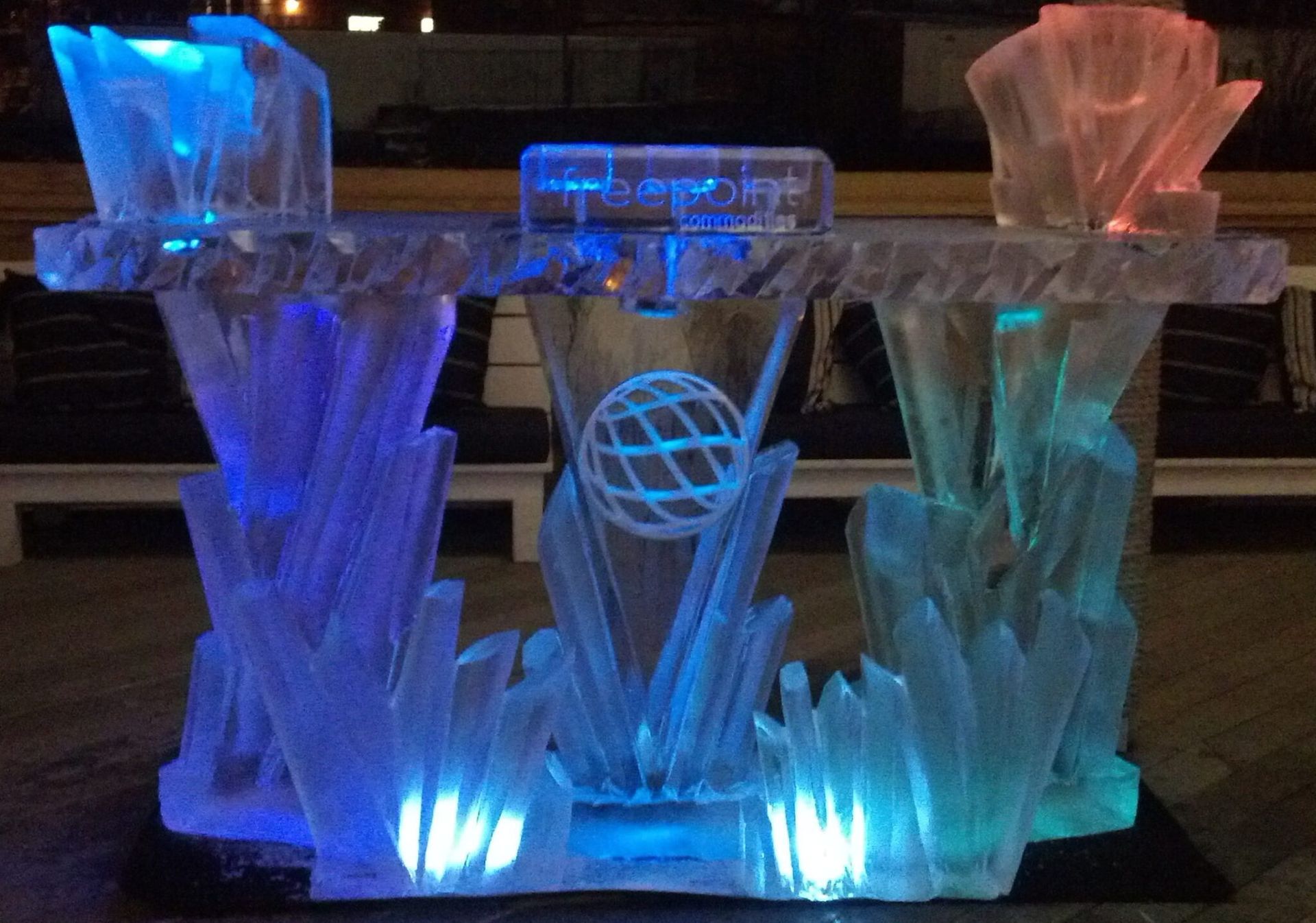 Colorful illuminated ice sculpture display glowing blue, teal, and pink at night