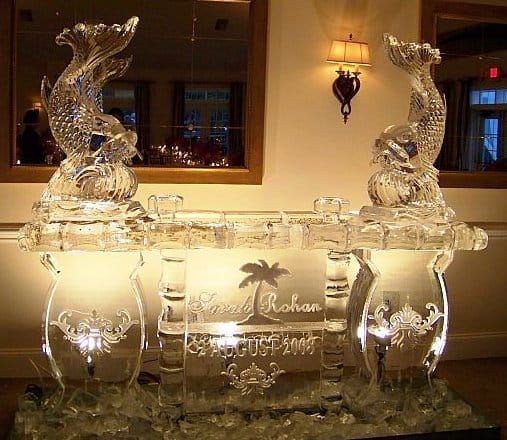 Decorative ice sculpture centerpiece with two seahorses and engraved glass, lit on a banquet table
